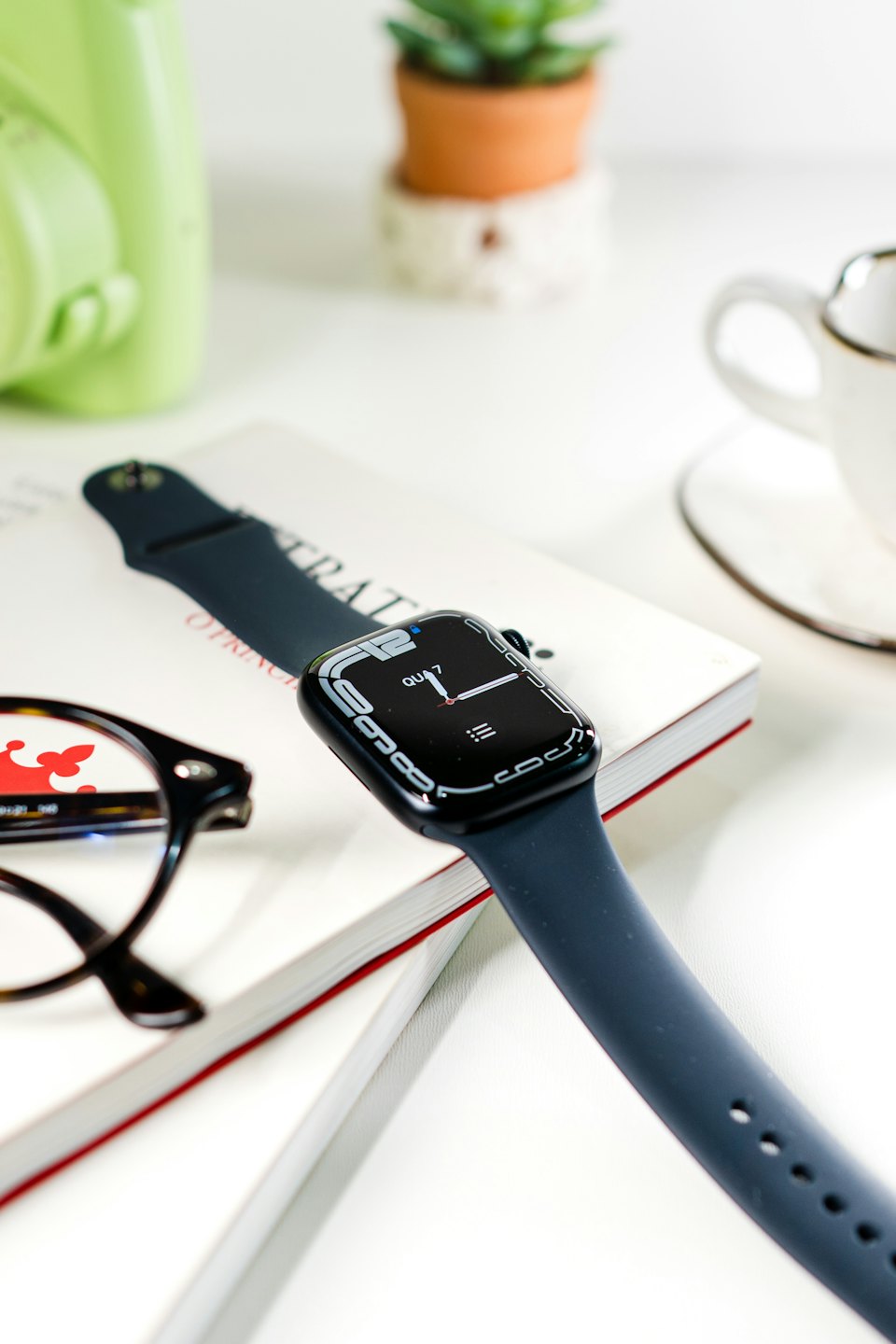 Smartwatch and eyeglasses on an open book.